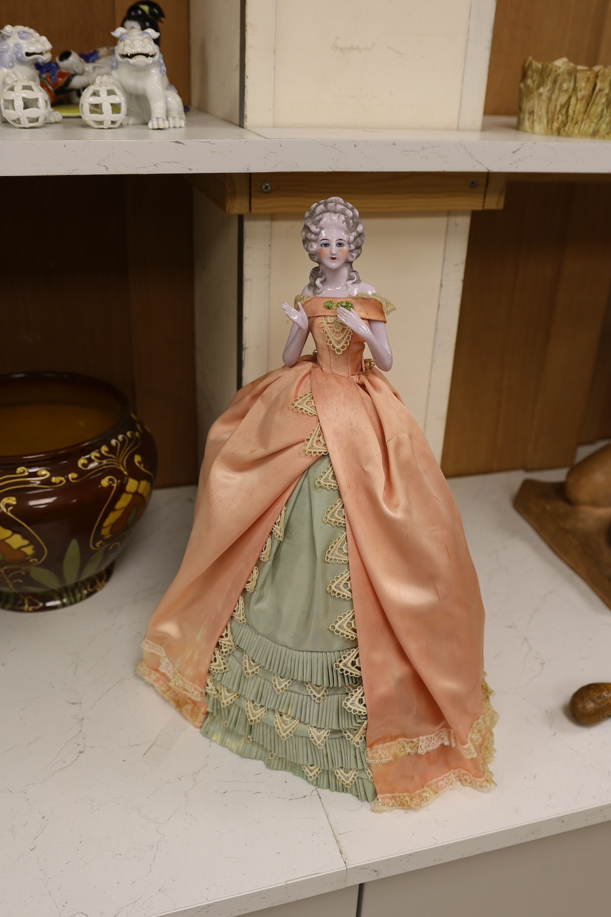 A 1920’s German porcelain 'pin dolly' with tea cosy dress, 46cm high. Condition - good some marks to the silk of cosy/dress